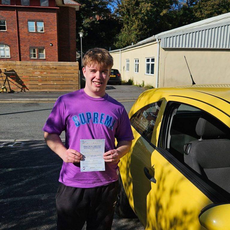 Young man in a purple t-shirt holding a certificate next to a yellow car.